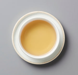 White ceramic bowl with three whites liqueur on a gray background