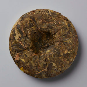 Grandpas Pocket huangpian sheng puer tea cake showing compressed aged tea leaves with golden brown hues