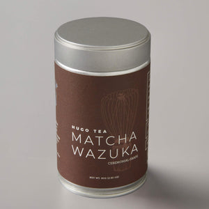 Matcha Wazuka ceremonial grade tea in cylindrical silver tin with brown label featuring minimalist whisk design