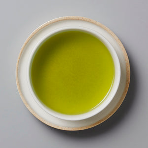 Sonogi Tama green tea served in white ceramic cup with beige rim, vibrant lime-green liquid viewed from above