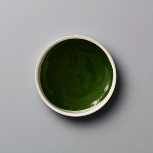 Matcha Kame ceremonial grade green tea powder in white ceramic bowl showing vibrant emerald color and smooth texture