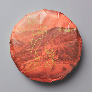 2020 Bruiser black tea cake with gold design on coral-colored wrapper showing mountain landscape