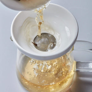 BOLI MINI 200ml glass pitcher with strainer, pouring golden tea through filter into clear vessel