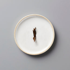 LINS DUCK dancong oolong tea leaf on white ceramic plate with beige rim against grey background