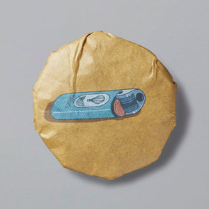 Smoke Break black tea cake with blue tea wrapper illustration on tan compressed disc of artisanal lapsang souchong
