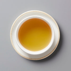 Golden Japanese Tea Flower tisane in white ceramic cup viewed from above, showing amber-colored liquid