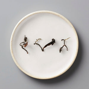 Champagne Long Kou oolong tea leaves artfully arranged on white ceramic plate showing natural twists and curves