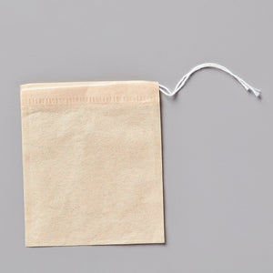 Drawstring sachets for tea steeping: unbleached cotton cellulose bag with white string closure on gray background