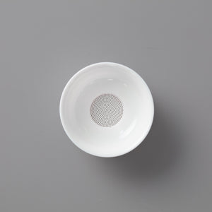 White porcelain filter with perforated base featuring multiple tiny holes on elegant circular stand for tea straining