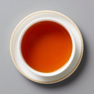 Fyn Rooibos tisane in white ceramic cup showing rich amber-red liquid against grey background