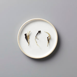 Ma Wei Moonlight white tea leaves displayed on white ceramic plate showing delicate dried buds and leaves arrangement