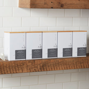 Storage Can MIYABI white tea tins with bamboo lids arranged on wooden shelf against white tile wall