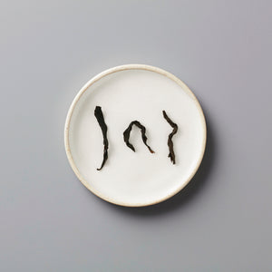 Zi Ran Smoke black tea leaves arranged artistically on white ceramic plate showing natural curved shapes