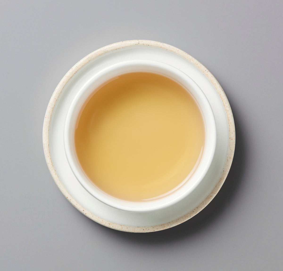 White ceramic bowl with three whites liqueur on a gray background