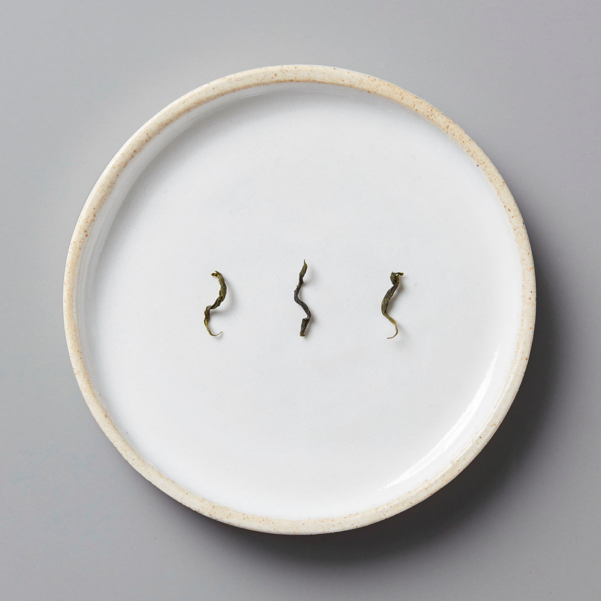 Anshun Maofeng green tea leaves displayed on white ceramic plate showing twisted leaf shape and quality