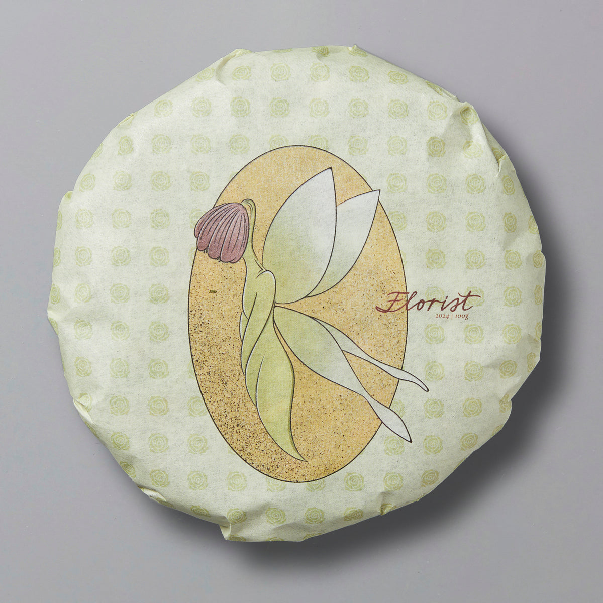 A pressed white tea cake with a floral design and the word 'Florist' printed on the top surface, against a patterned background.