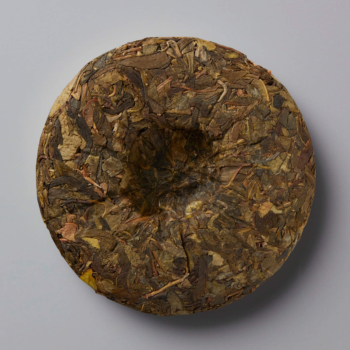 Grandpas Pocket huangpian sheng puer tea cake showing compressed aged tea leaves with golden brown hues