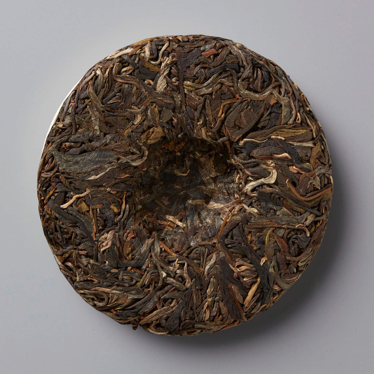 MADE-FOR-TV sheng puer tea cake showing compressed dark and golden tea leaves in traditional circular disc form