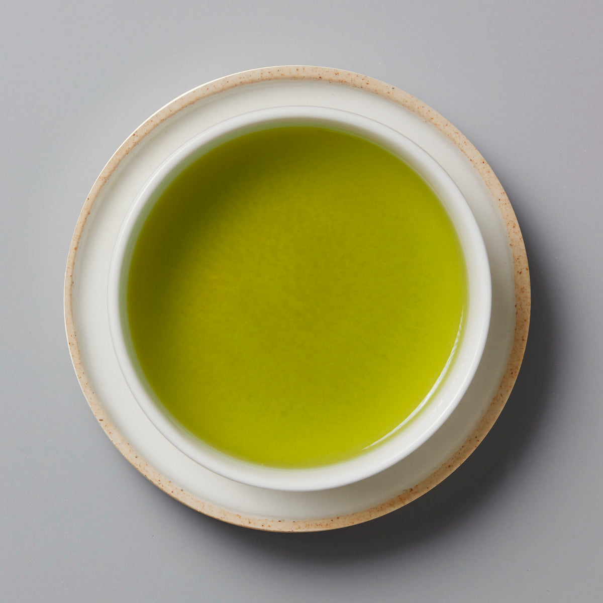 Sonogi Tama green tea served in white ceramic cup with beige rim, vibrant lime-green liquid viewed from above