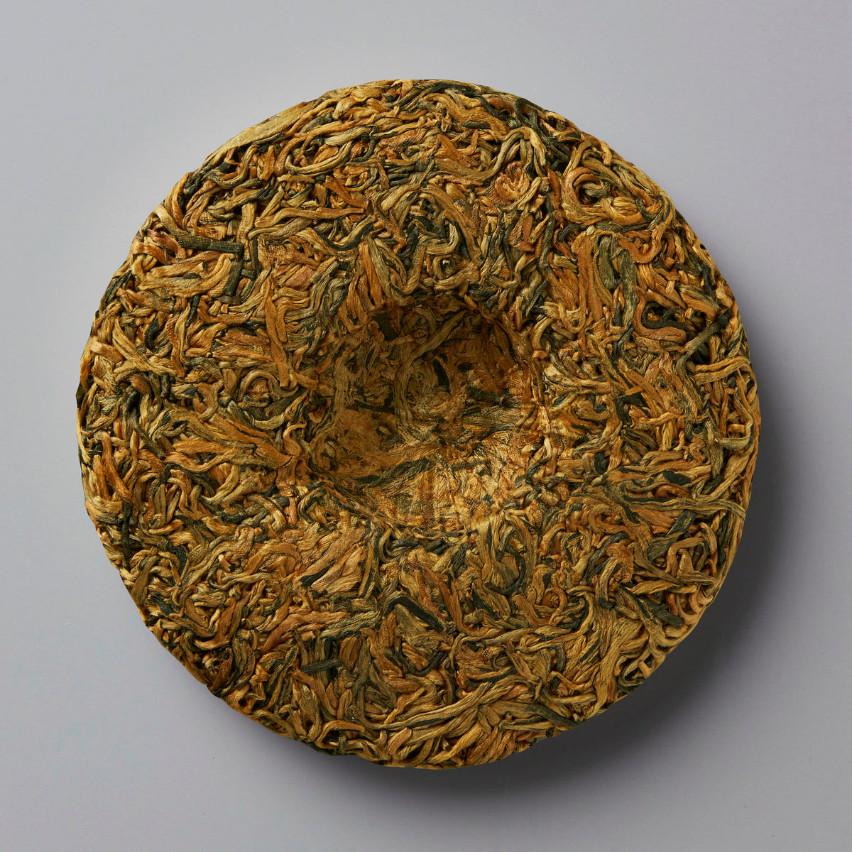2023 Tree Sap black tea cake showing compressed golden buds in circular form against grey background