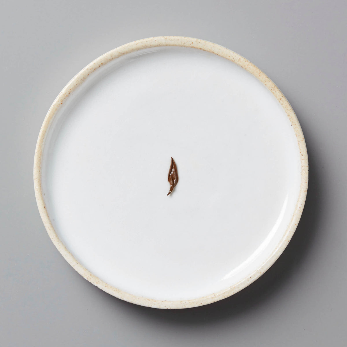 Anshun Jin Jun Mei black tea bud on white ceramic plate with beige rim against gray background
