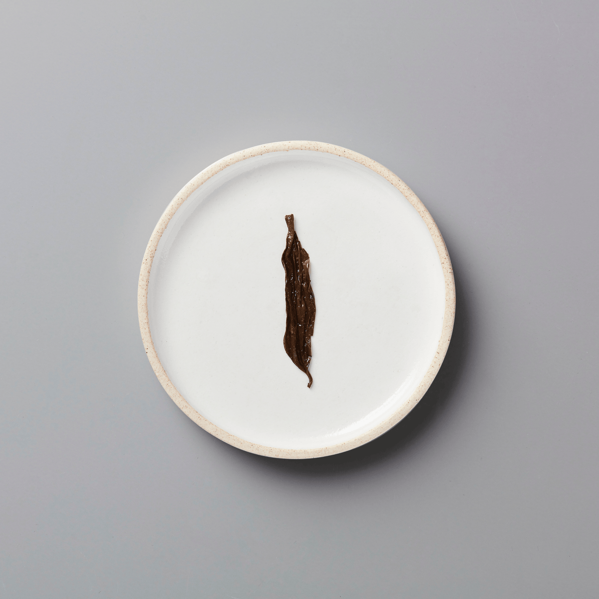 PANLAN 105 yancha oolong tea leaf displayed on white ceramic plate against grey background