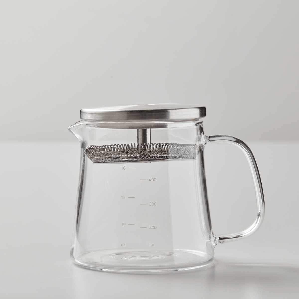 BOLI teapot with clear glass body, metal lid, measurement markings and ergonomic handle on white background