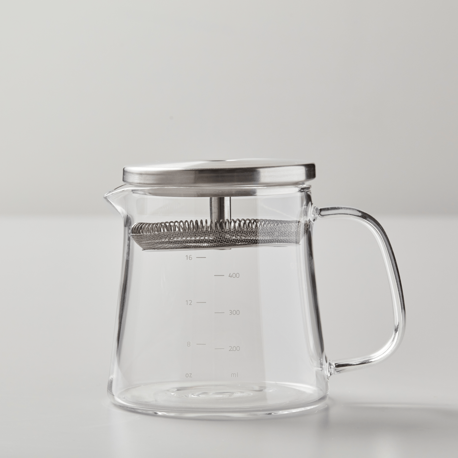 BOLI teapot with clear glass body, metal lid, measurement markings and ergonomic handle on white background
