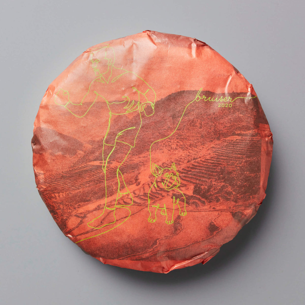 2020 Bruiser black tea cake with gold design on coral-colored wrapper showing mountain landscape