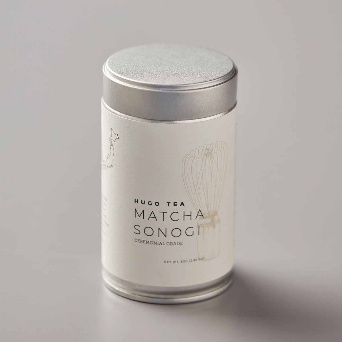 Matcha Sonogi ceremonial grade tea in elegant white cylindrical tin with silver lid on gray background