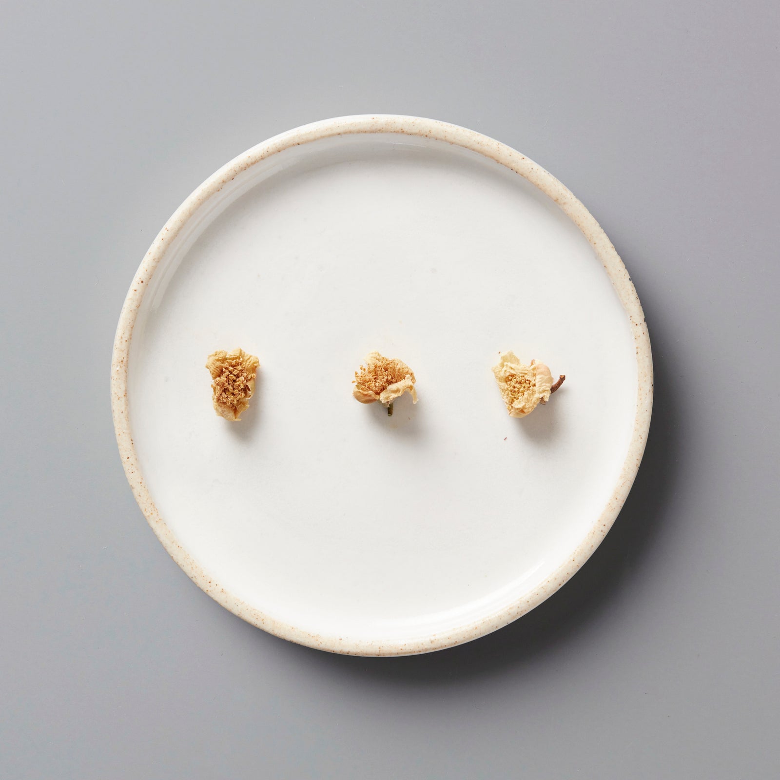 Dried tea flowers from Wazuka, Japan displayed on white ceramic plate showing TEA FLOWER tisane blooms
