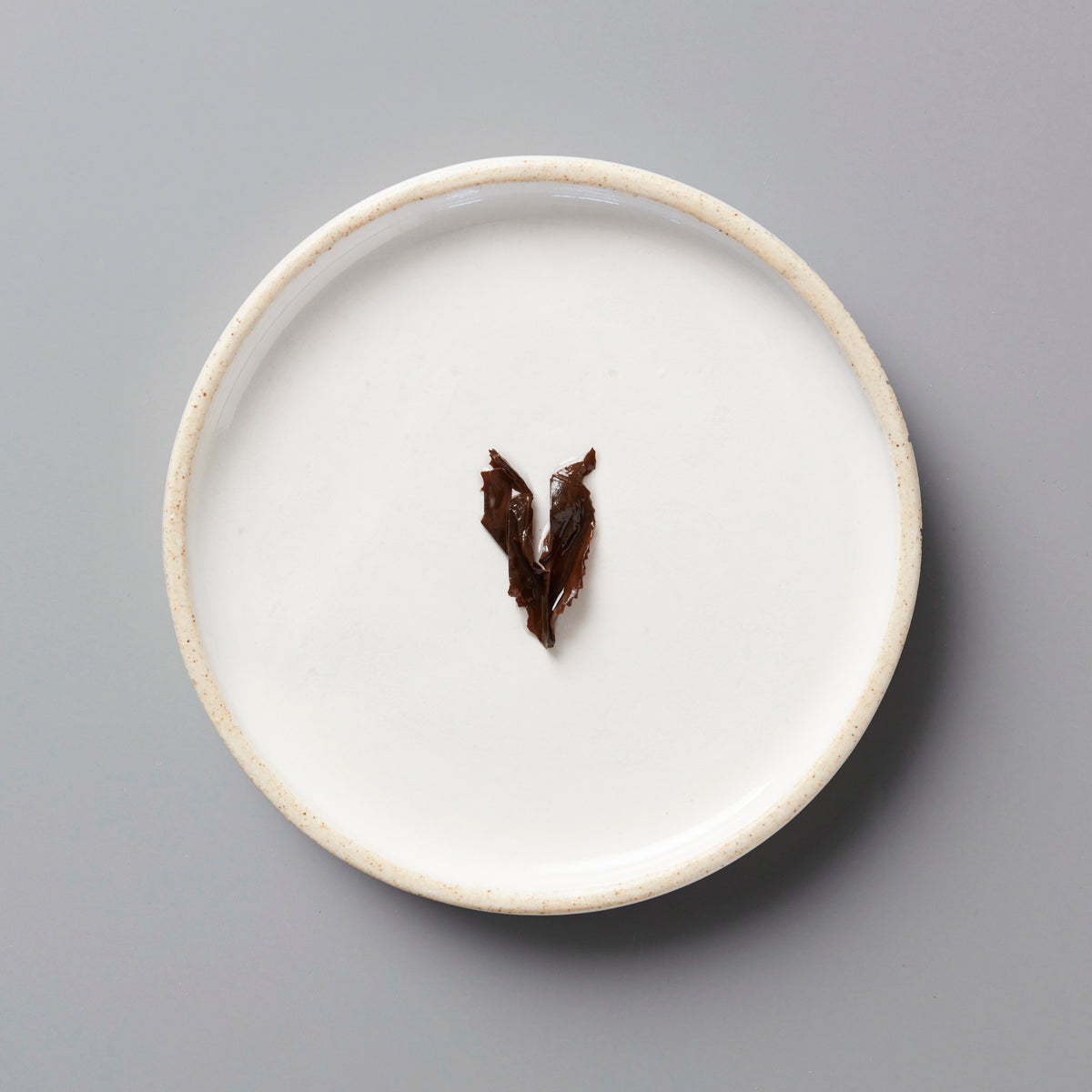 ZI RAN RED black tea leaves on a minimalist white ceramic plate with raised rim, showcasing traditional Tongmu tea