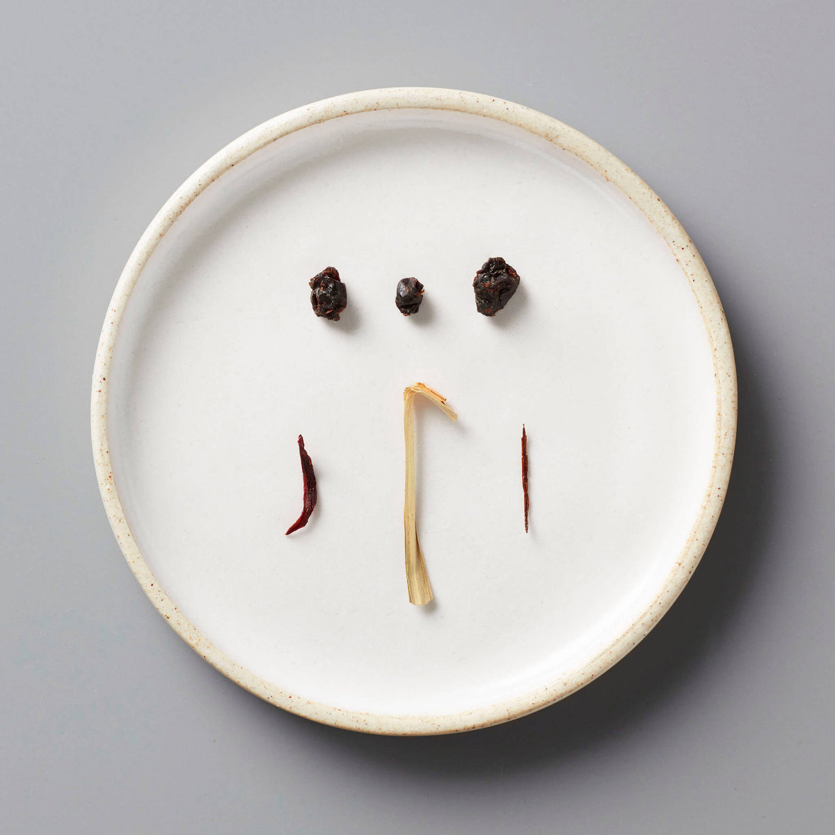 CURRANT tisane blend ingredients artfully arranged on white ceramic plate showing dried currants and herbs