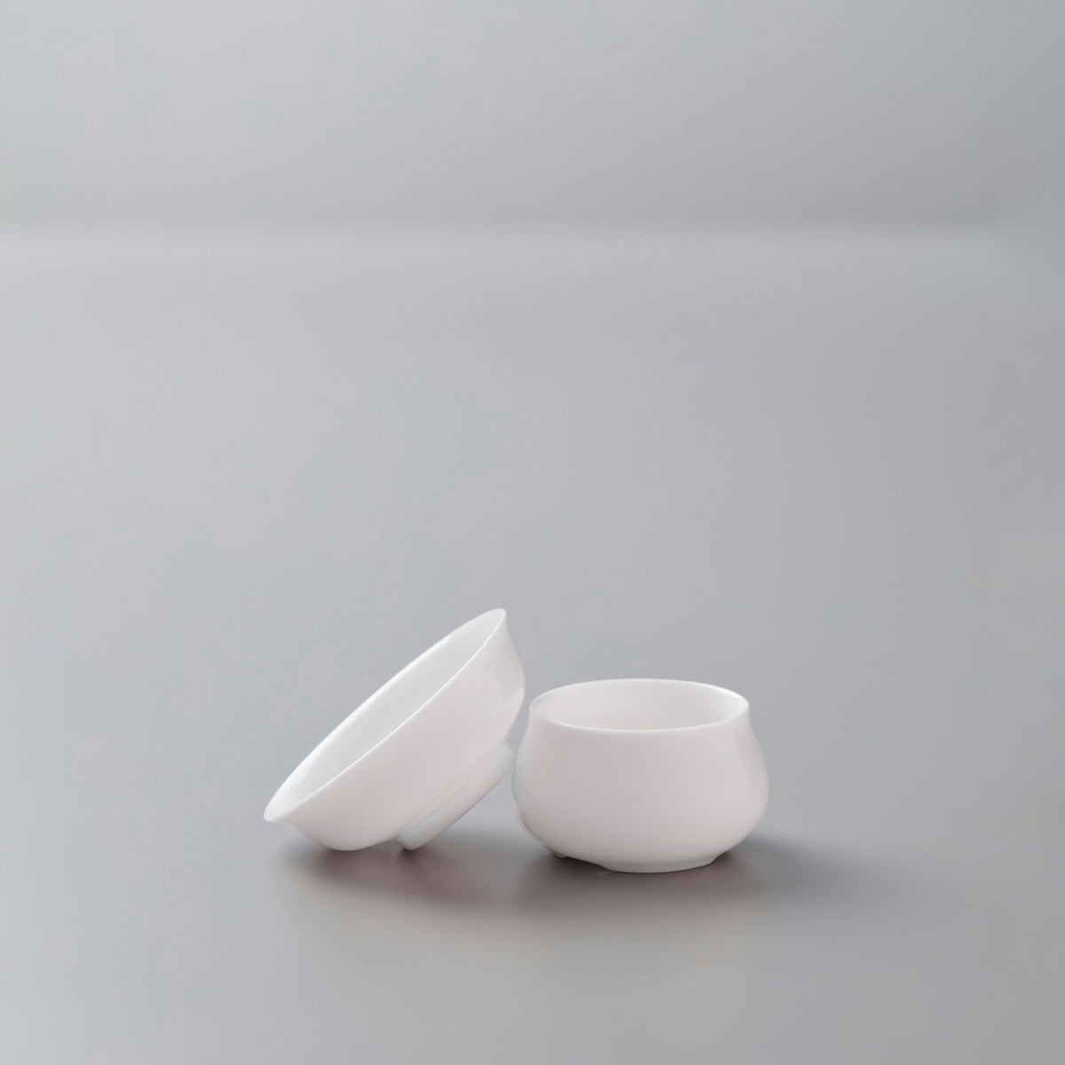 White porcelain filter and stand set for tea brewing, featuring conical strainer and round drip catch base