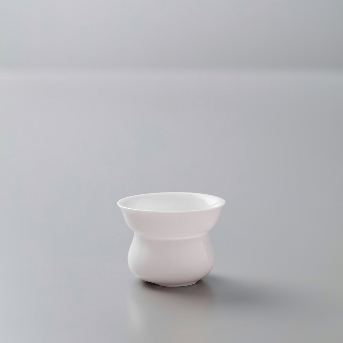 Elegant white porcelain filter stand for tea preparation, part of the PORCELAIN FILTER set on minimalist grey background