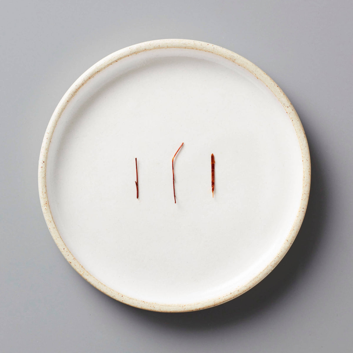 FYN ROOIBOS tisane needles displayed on white ceramic plate showing natural reddish color and long-cut strands