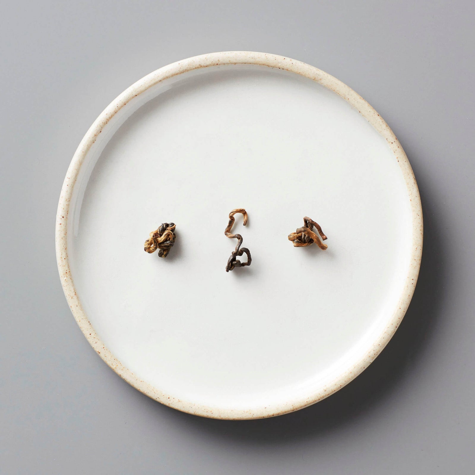 GAO WEN black tea leaves arranged on white ceramic plate showing oxidized twisted leaf shapes and characteristic color
