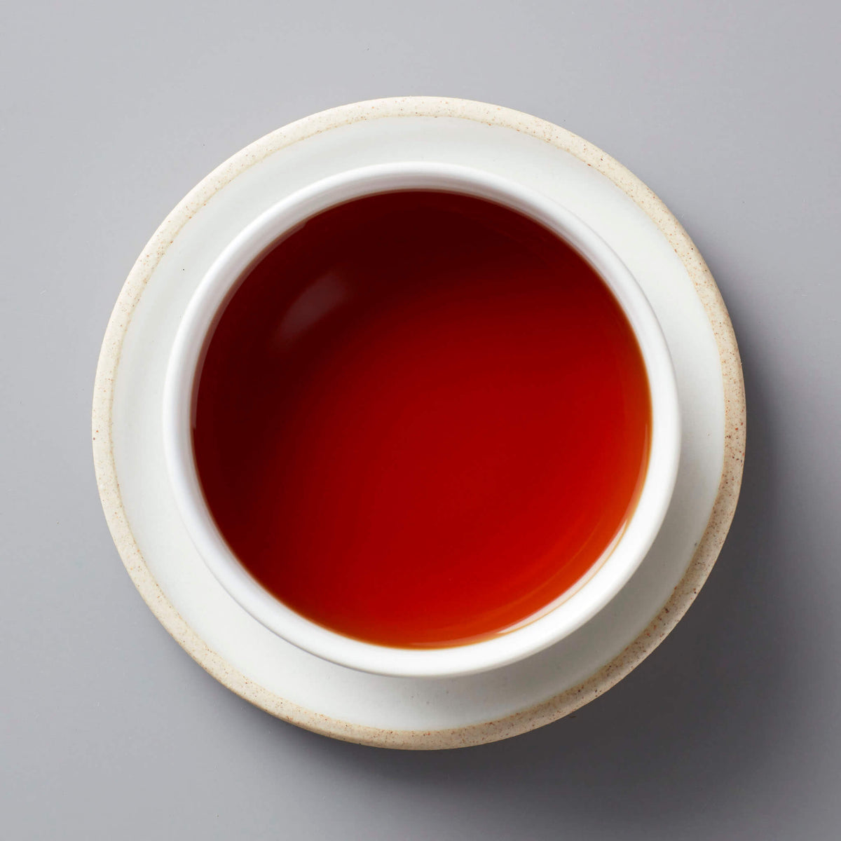 Hugo Grey black blend tea in white ceramic cup with rich reddish-brown liquor on grey background
