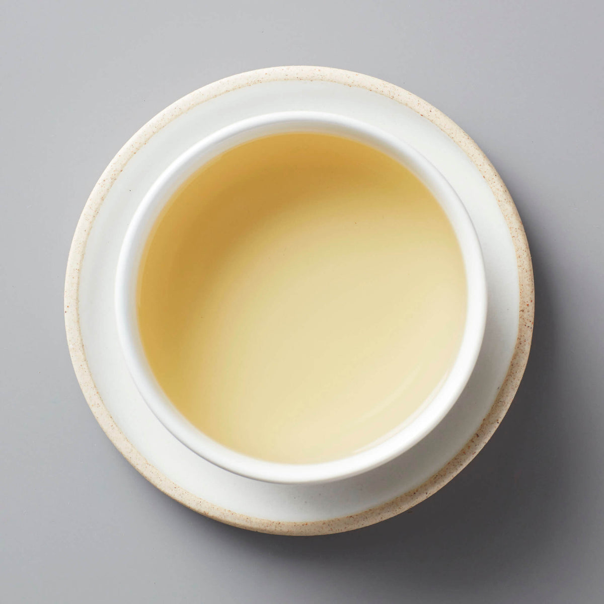 GUI SHAN oolong tea in white ceramic cup with pale golden liquor against grey background