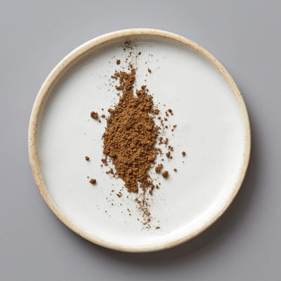 HOUJI POWDER HUGO green tea powder scattered on white ceramic plate with beige rim