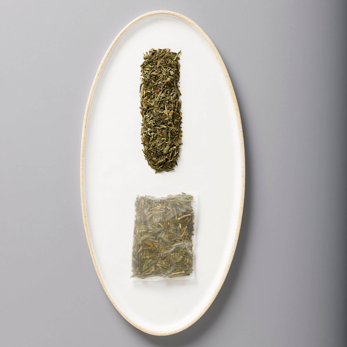 Iced Classic Green tea leaves and sachet displayed on white oval ceramic plate