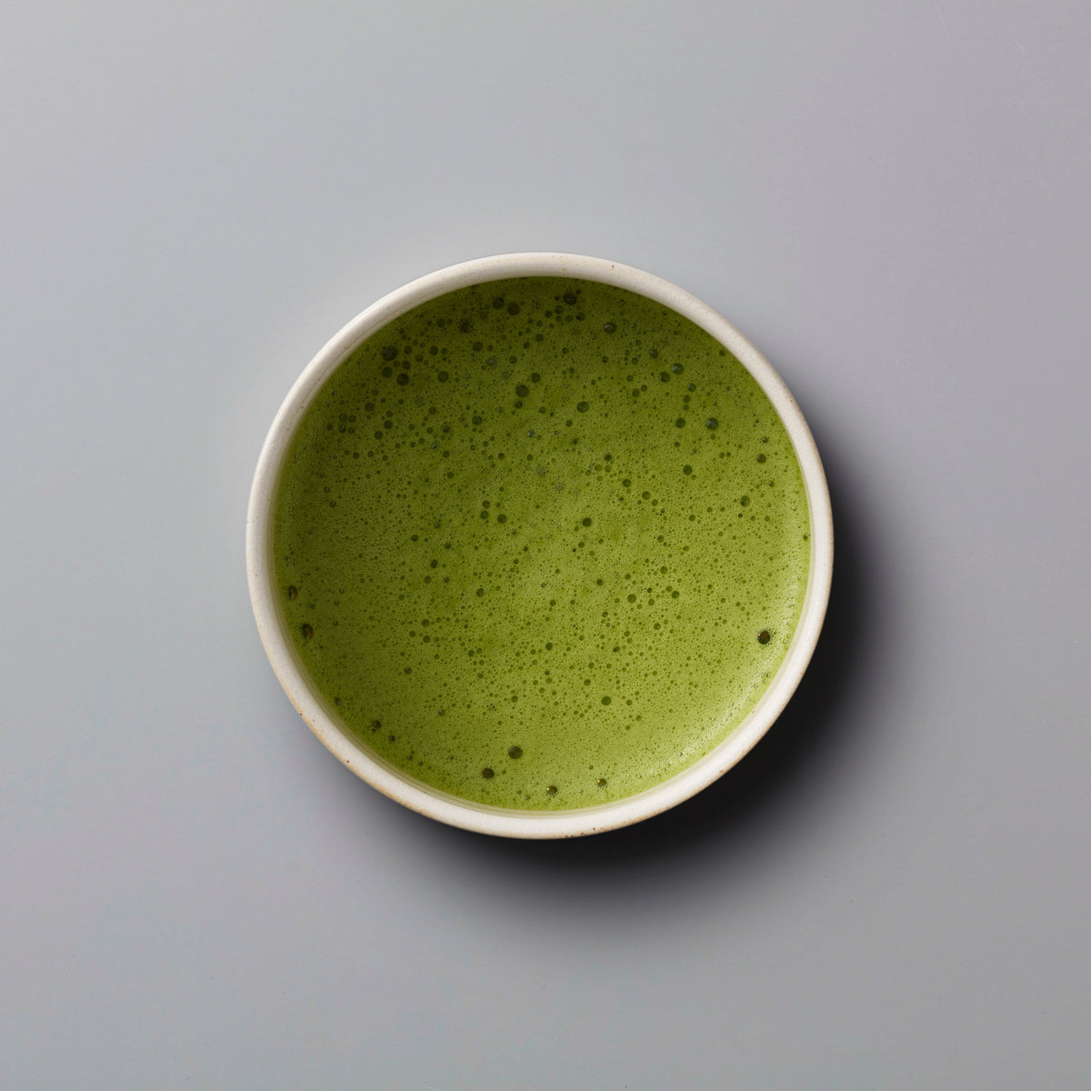 Matcha Sonogi ceremonial grade tea in white ceramic bowl with frothy bright green surface and fine bubbles