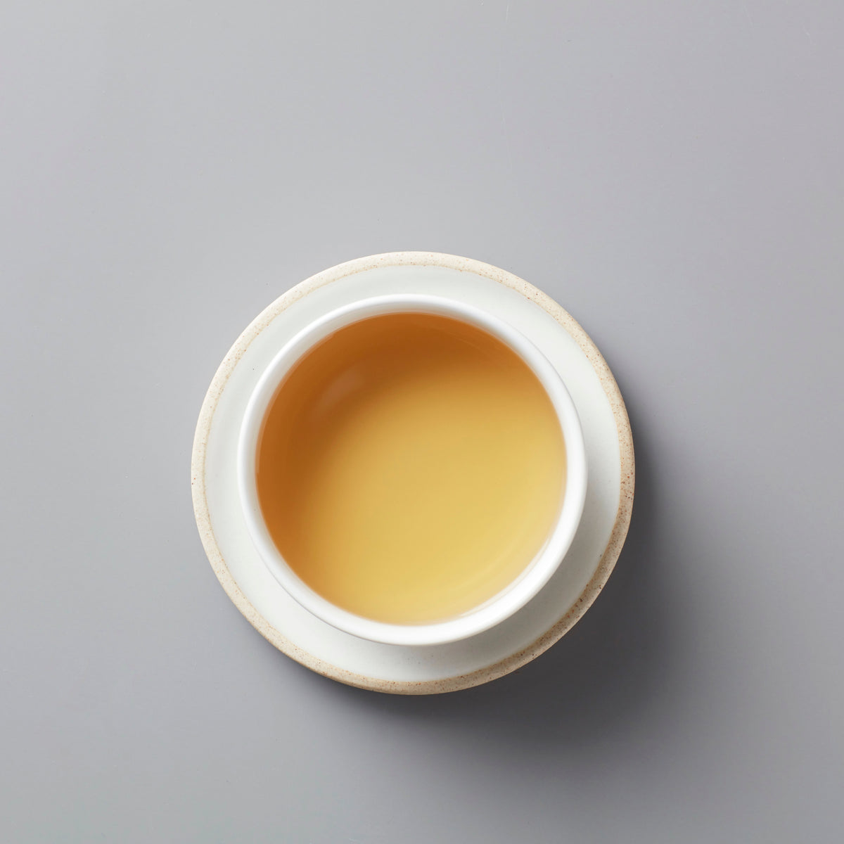 MA WEI MOONLIGHT white tea in ceramic cup, showing golden amber liquid from above view on grey background