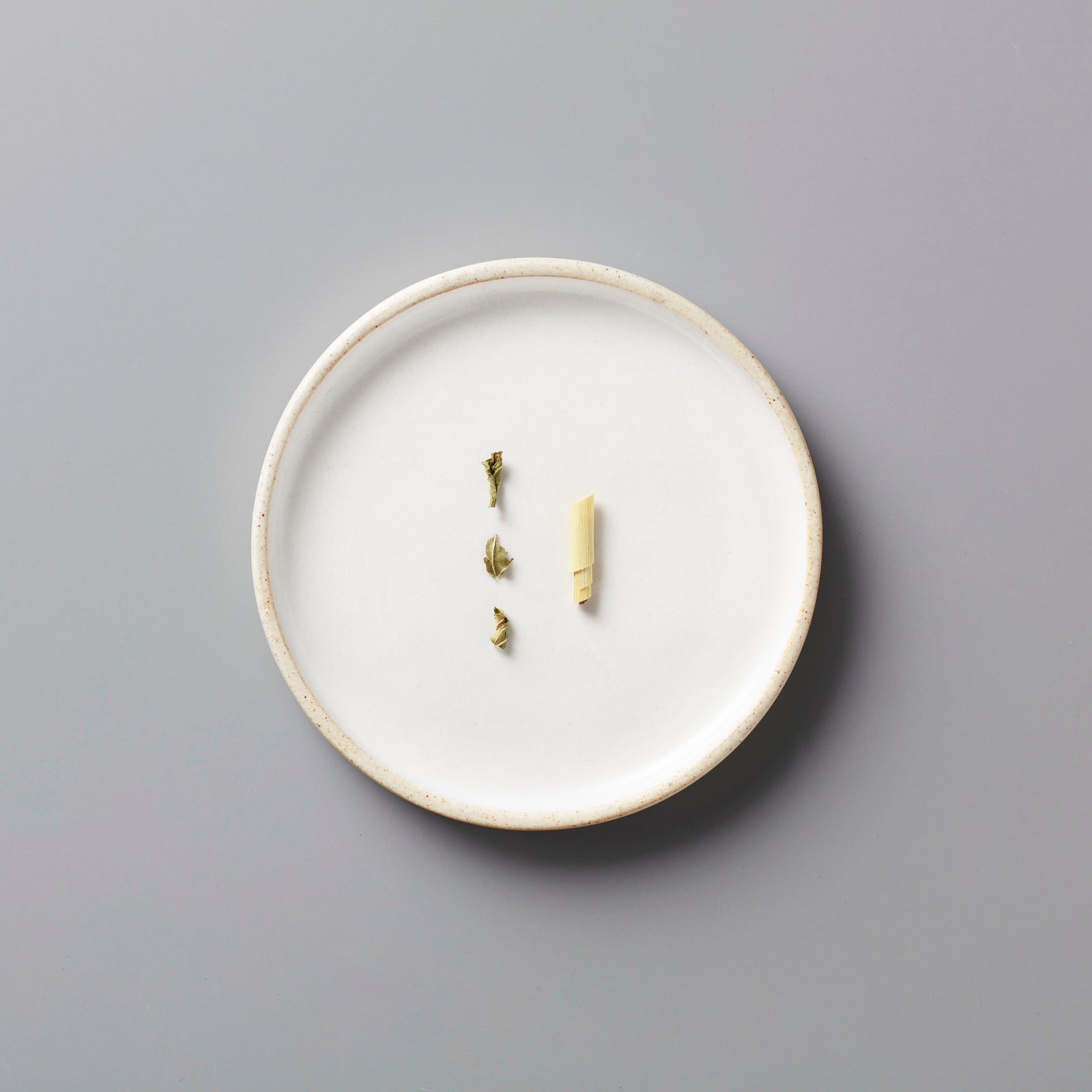 Rainier tisane blend ingredients displayed on minimalist white ceramic plate against grey background