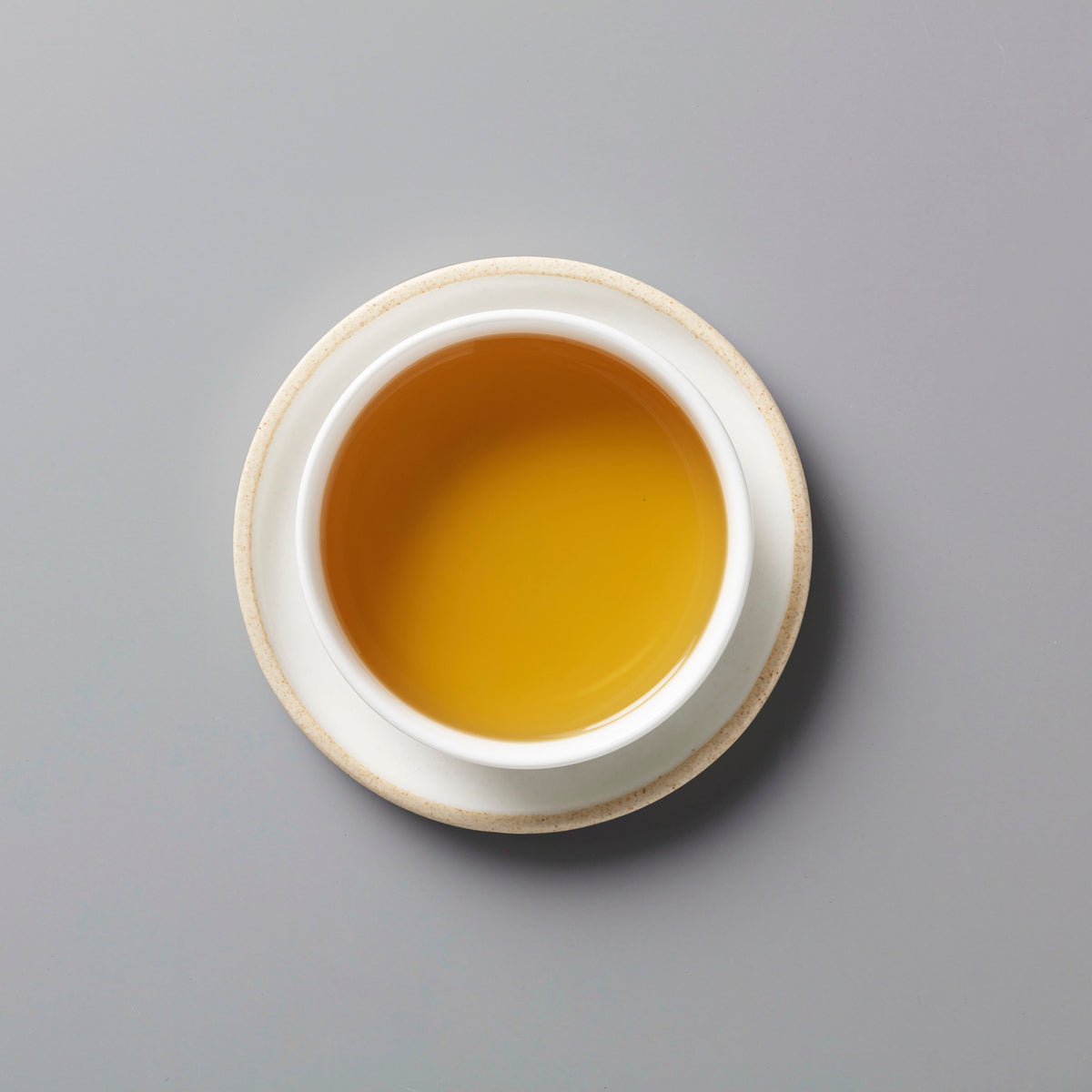 RAINIER tisane blend in white ceramic cup showing golden-orange liquor from above on grey background