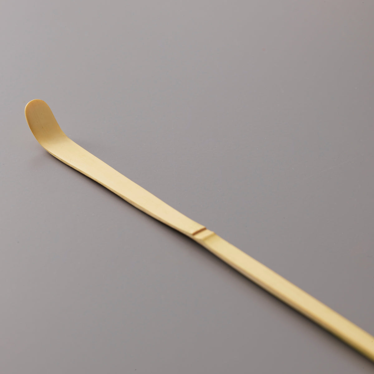 Traditional bamboo Matcha Scoop Chashaku with curved tip for precise tea measuring on grey background
