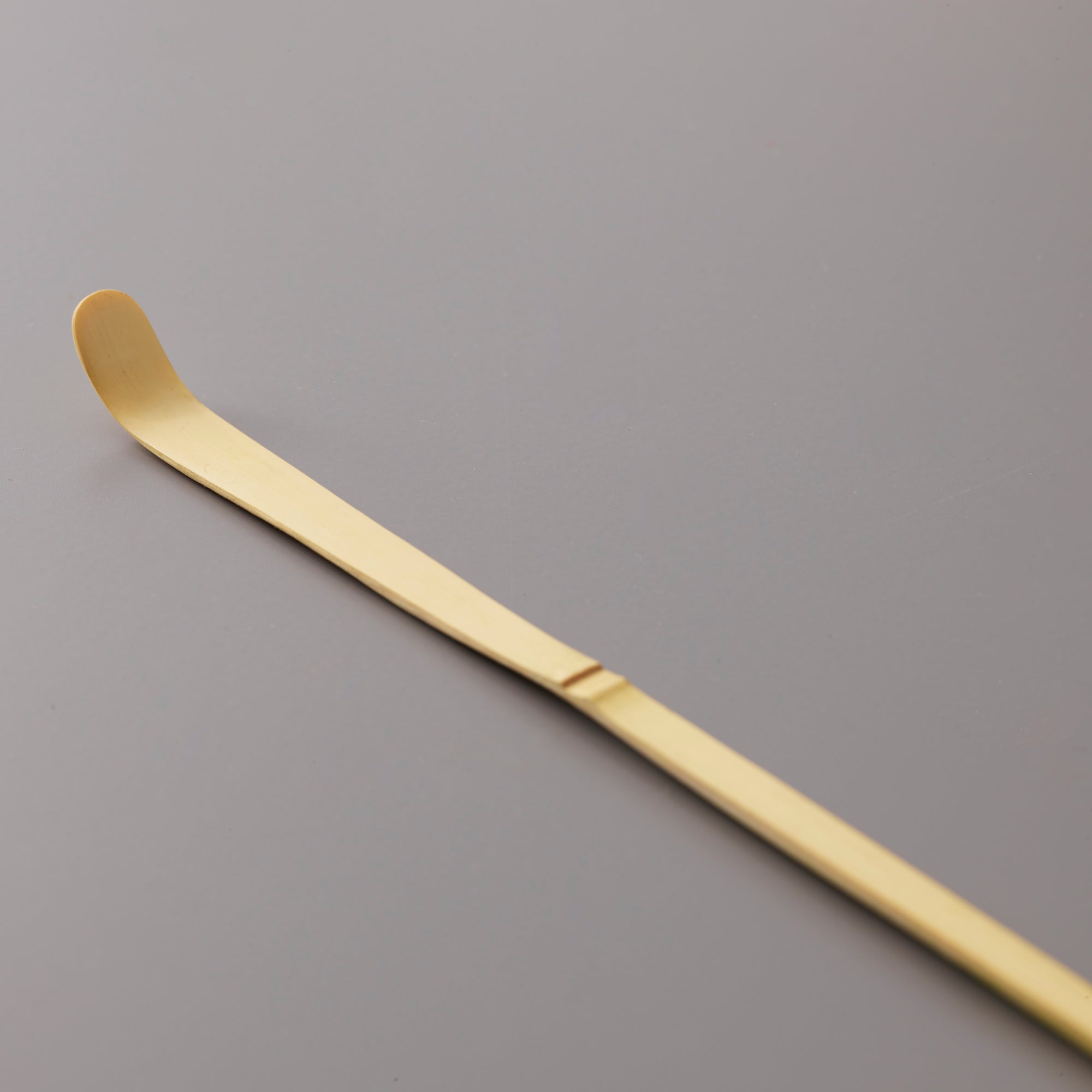 Traditional bamboo Matcha Scoop Chashaku with curved tip for precise tea measuring on grey background