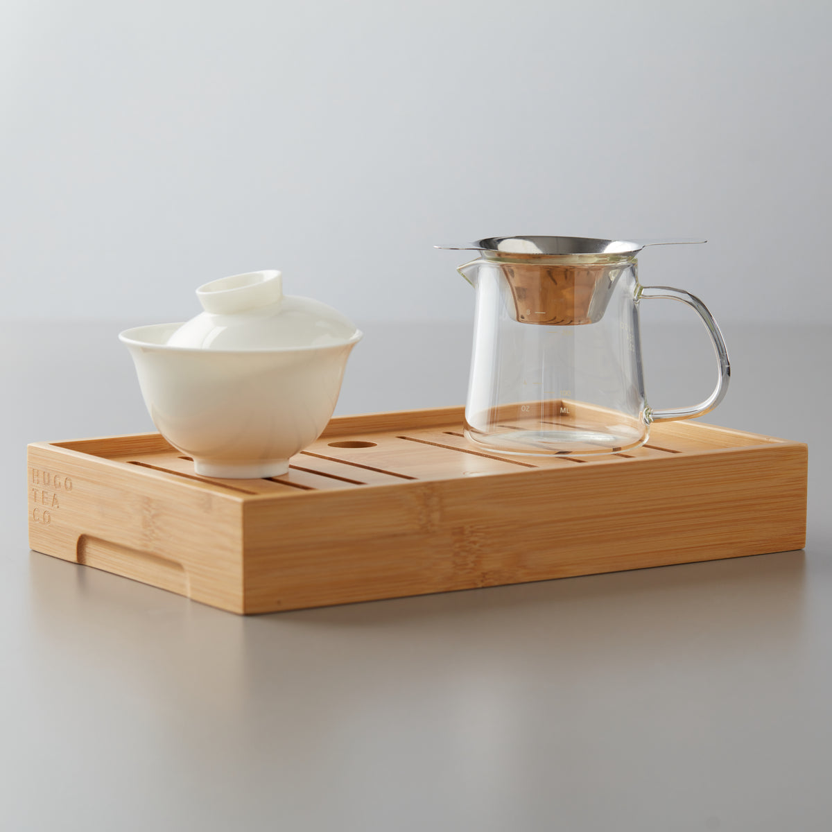 Bamboo TEA BOARD HUGO with gaiwan and glass pitcher for small-format gongfu tea steeping sessions.