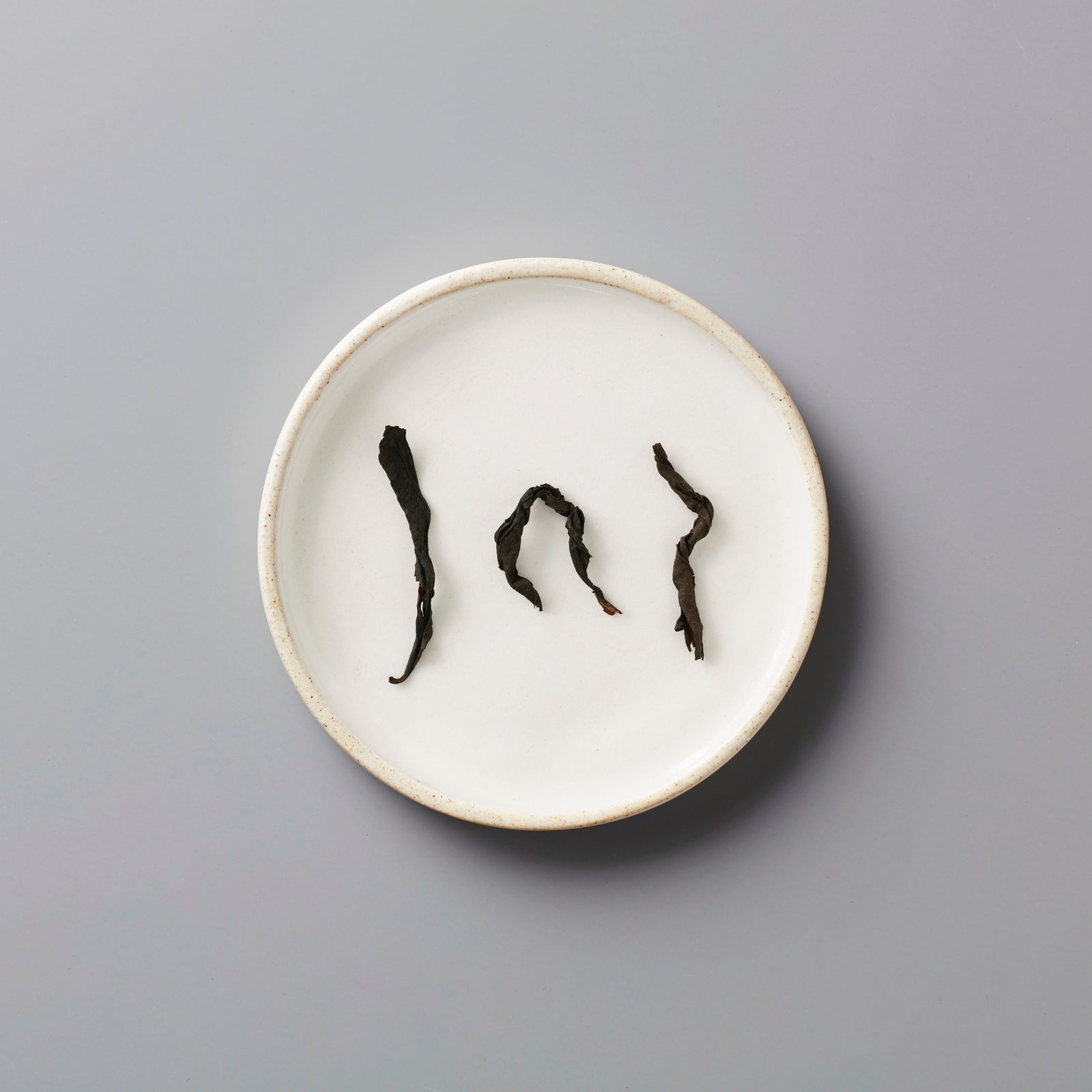 Zi Ran Smoke black tea leaves arranged artistically on white ceramic plate showing natural curved shapes